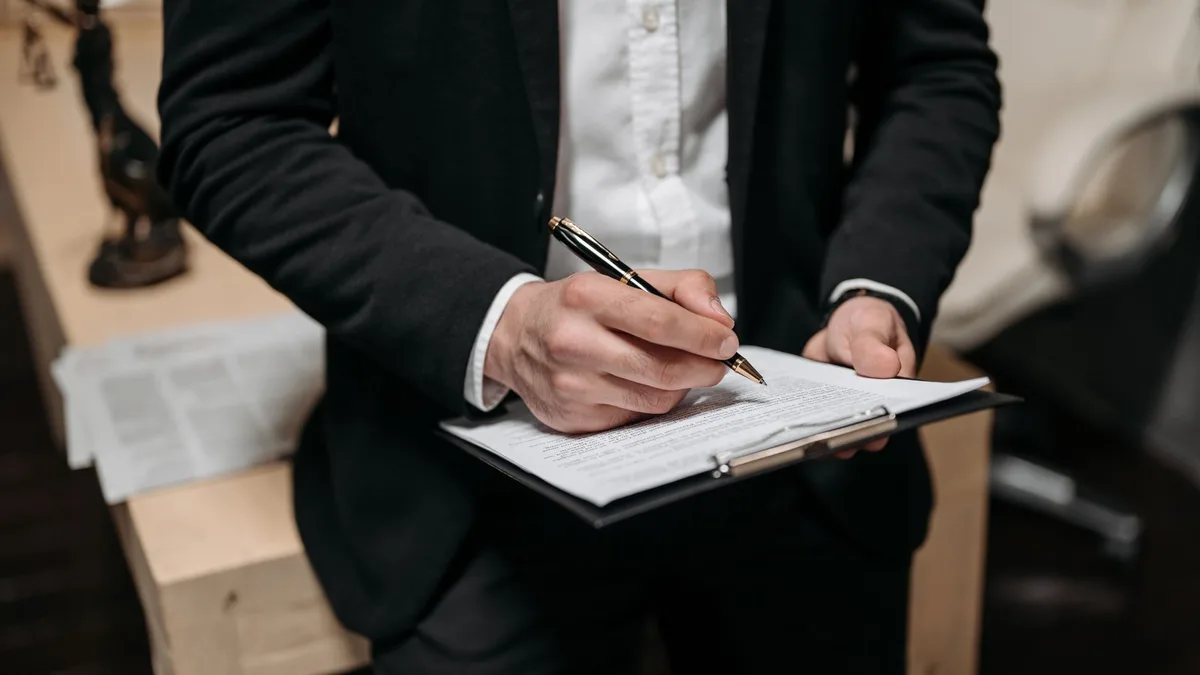 Signature d'un acte sur porte-bloc, geste caractéristique du notaire