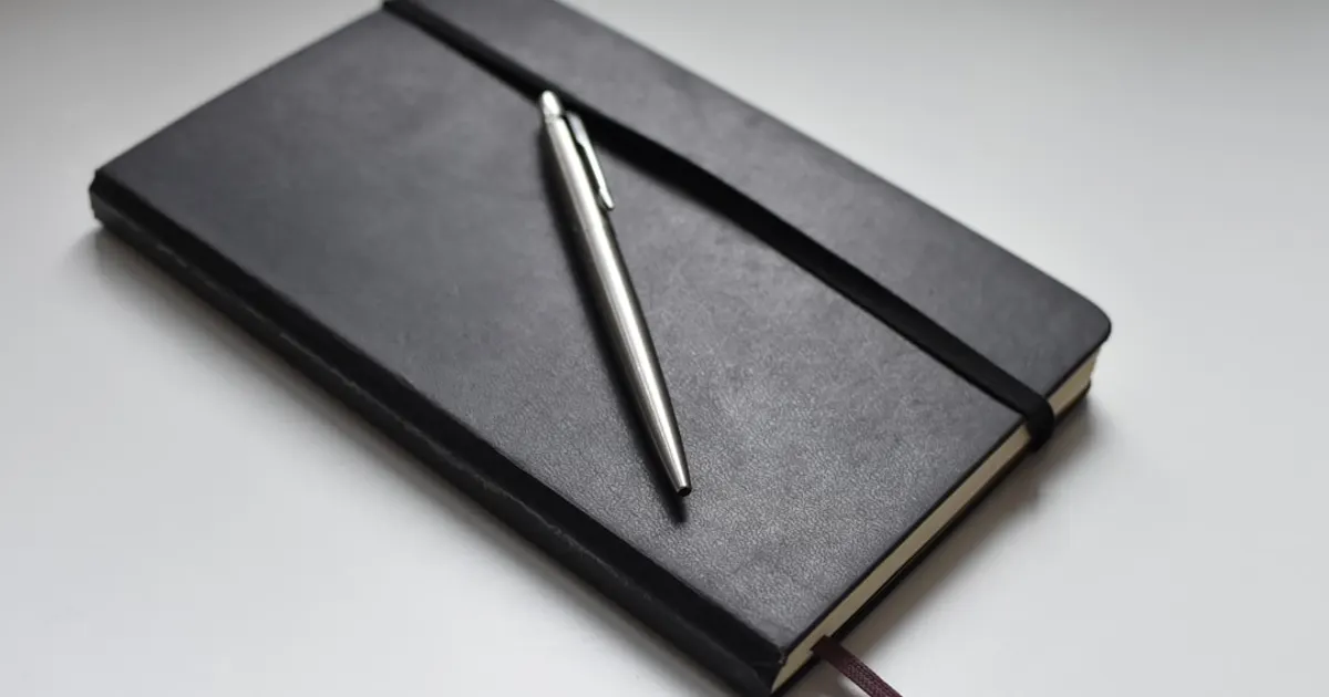 Carnet en cuir noir et stylo argenté, symbole du dossier de retraite complémentaire du notaire